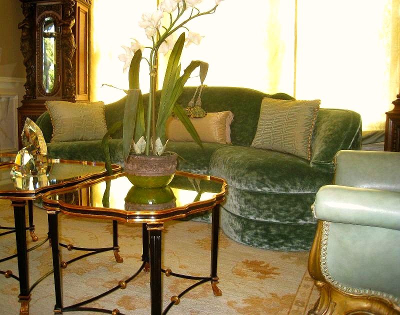 A living room with green furniture and gold tables