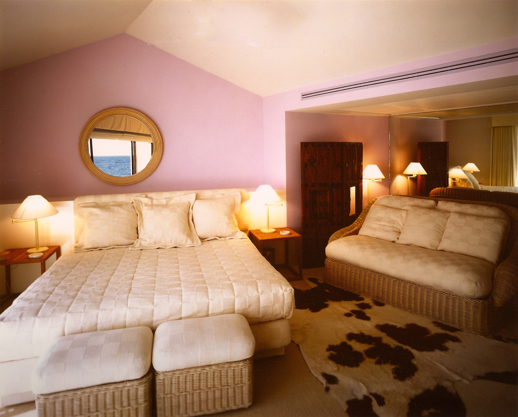 Vacation Condo Interiors. Main bedroom wall reflecting Ocean view, soft pink walls and wicker furniture at Puerto Aventuras Yacht Club Penthouse, a Jerry Jacobs Design ©