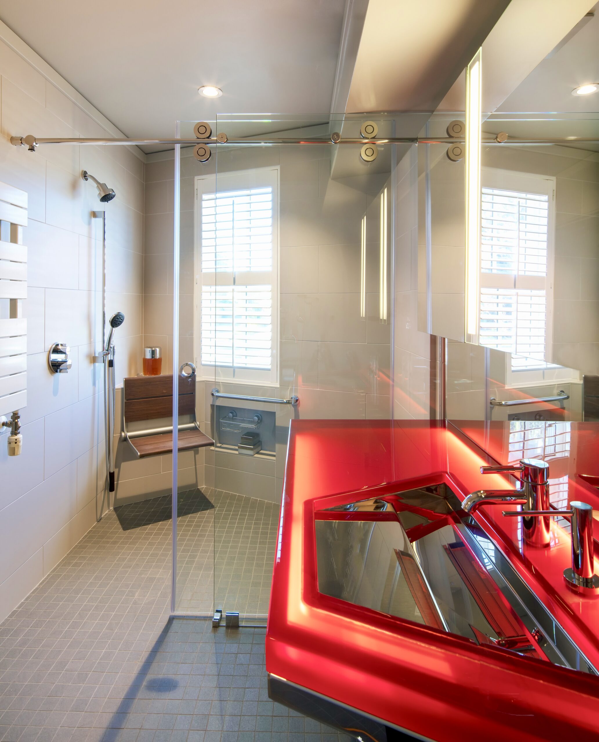 Contemporary bathroom design. Backlit resin top, glass barn doors and curdles shower with bench and hand shower. Design by Jerry Jacobs Design.