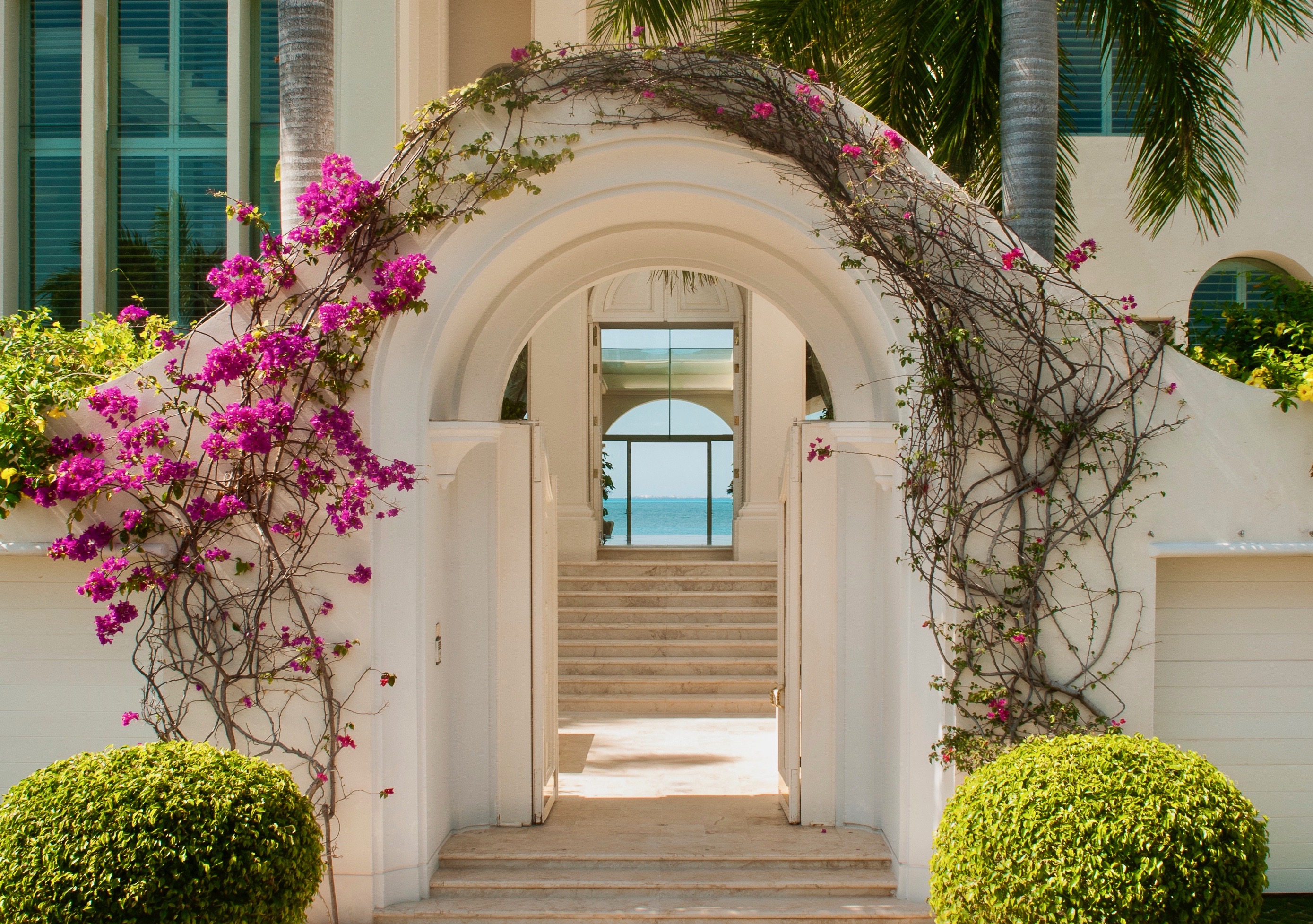 Tropical Style Interiors by Jerry Jacobs Design © Caribbean boutique hotel entrance, bougambilia on arch and Ocean view.