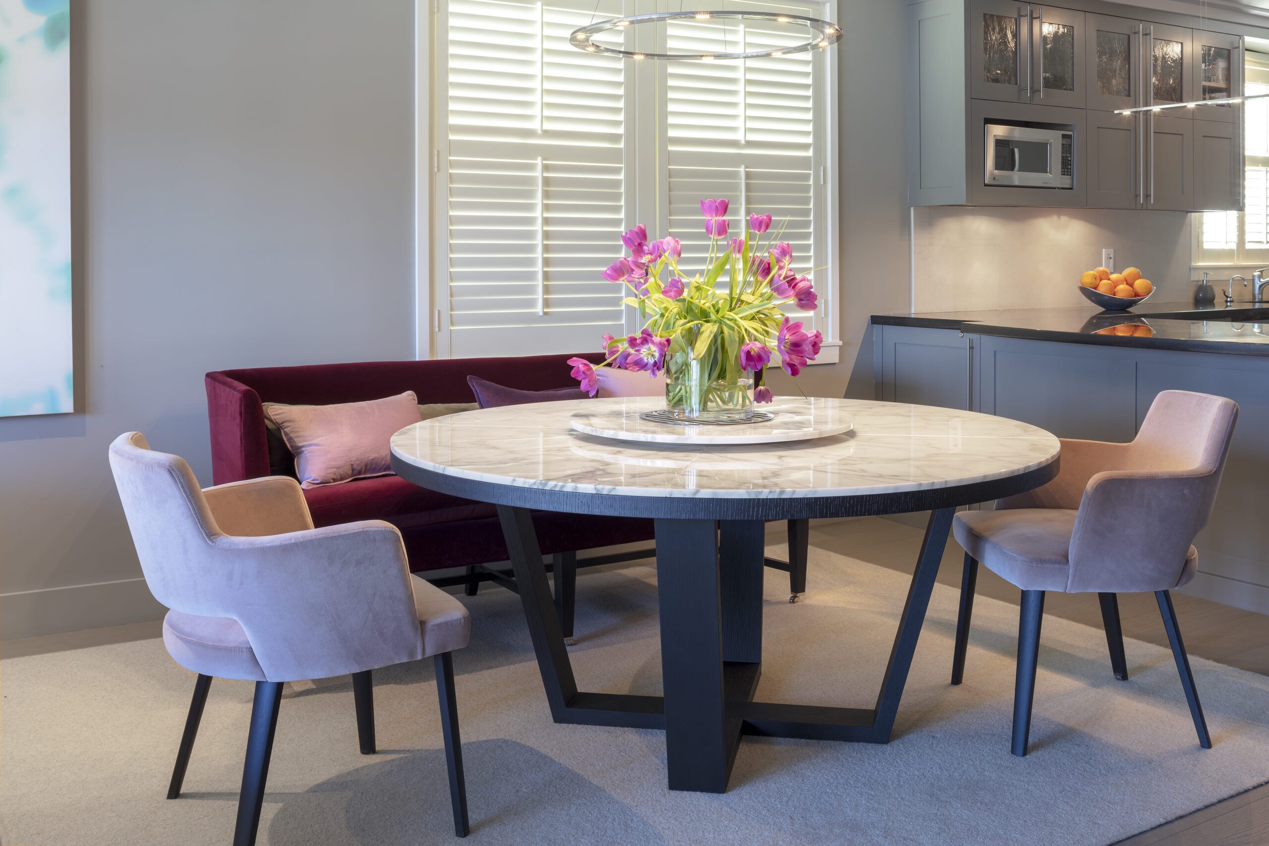 A dining room table with pink pillows and flowers in the center.