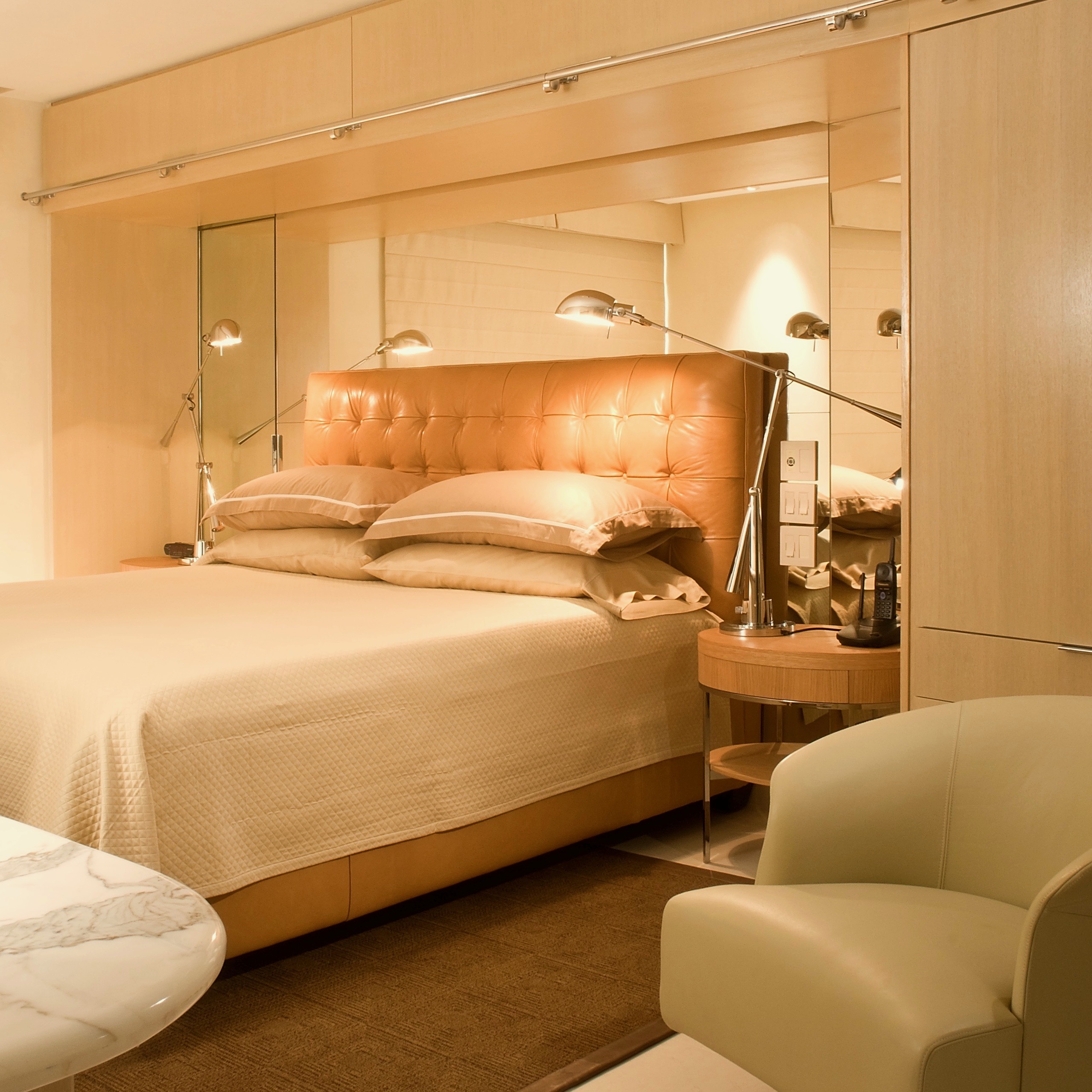 A bedroom with a bed, chair and mirror.